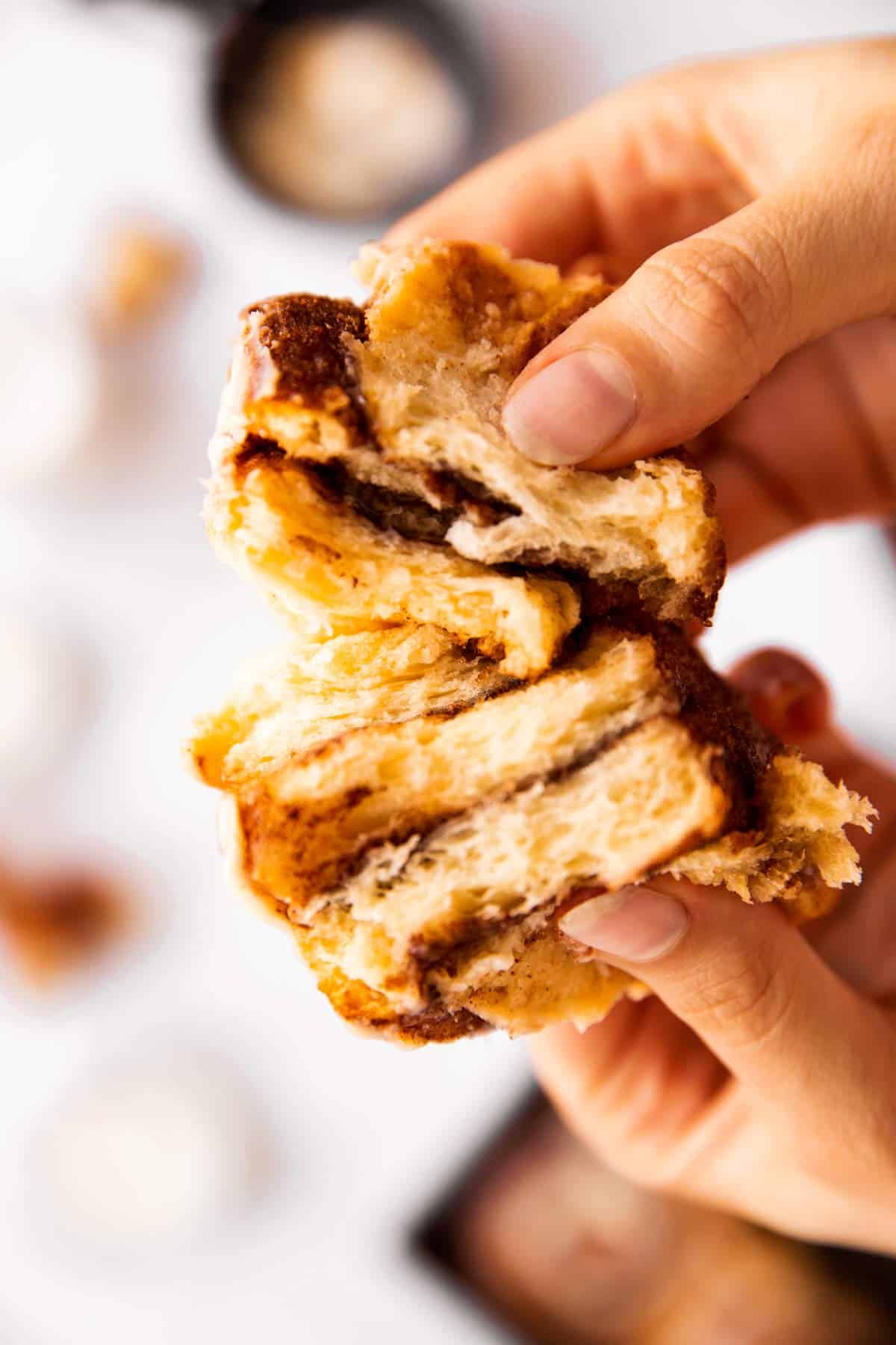 female hands breaking apart a cinnamon roll