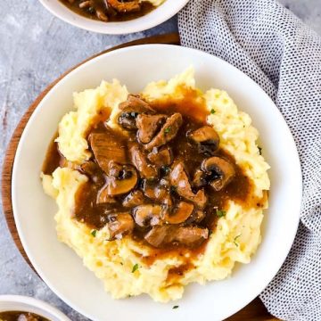 three plates with crockpot beef tips and gravy over mashed potatoes