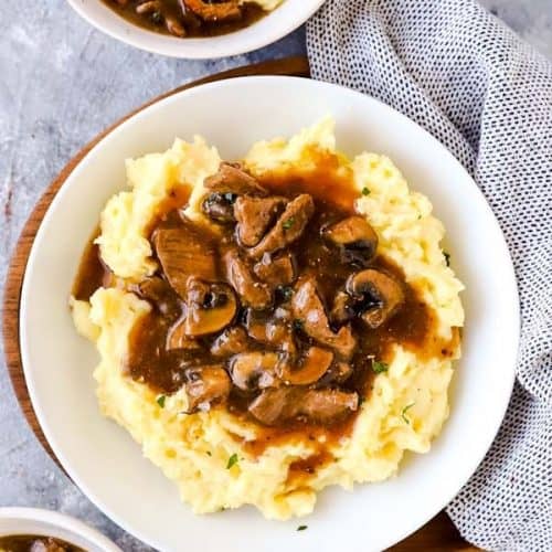 three plates with crockpot beef tips and gravy over mashed potatoes