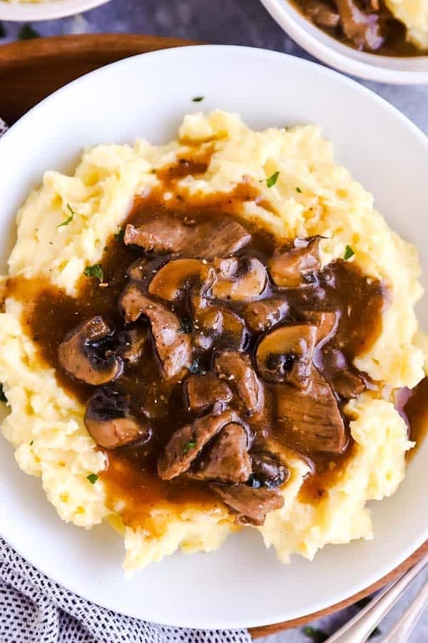 close up photo of a plate with mashed potatoes and beef tips and gravy