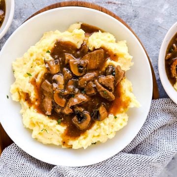 three plates with mashed potatoes and beef tips on a light surface