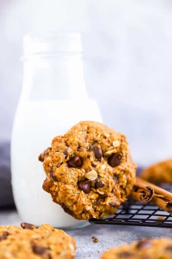 broken up close up photo of a Pumpkin Chocolate Chip Oatmeal Cookies leaning against a milk bottle