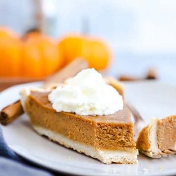 slice of pumpkin pie on a white plate with a bite taken out