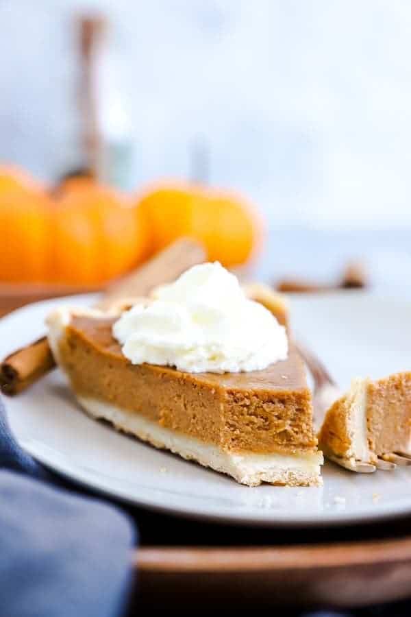 slice of pumpkin pie on a white plate with a bite taken out