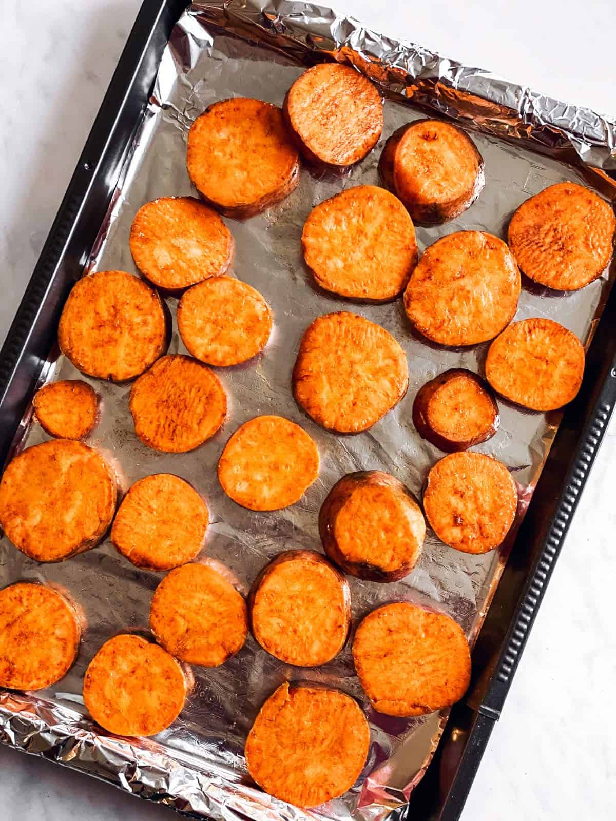 baking tray with raw sweet potato slices