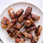 top down view on white plate filled with bacon wrapped dates