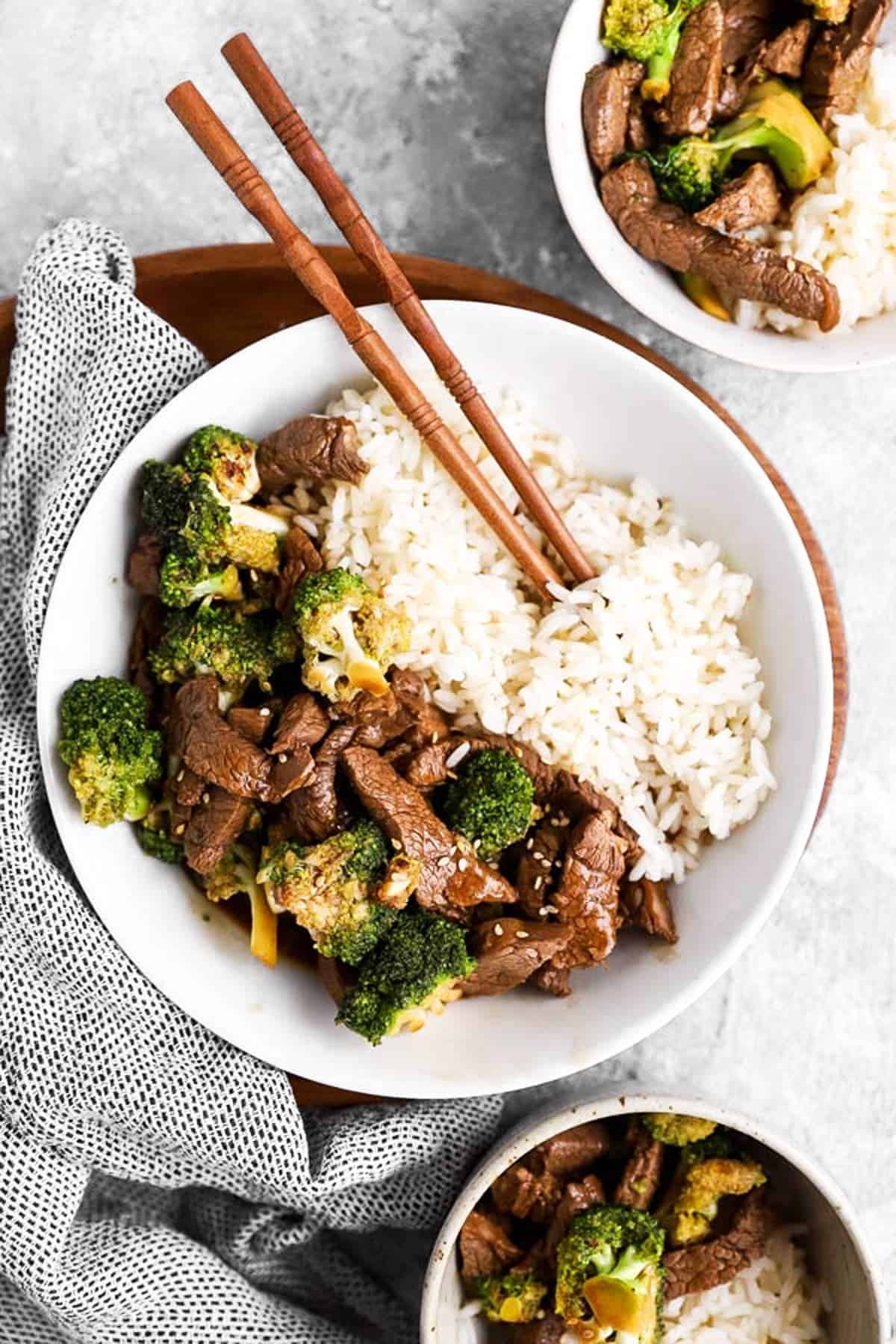 overhead view of beef and broccoli in white bowl with chopsticks