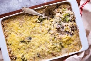 filled white casserole dish on a wooden board, spoon in