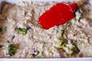 spreading chicken broccoli rice casserole mix in a white casserole dish