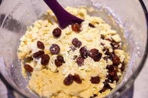 stirring dried cranberries and white chocolate chunks into cookie dough