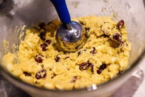 scooping white chocolate cranberry cookie dough with a cookie scoop