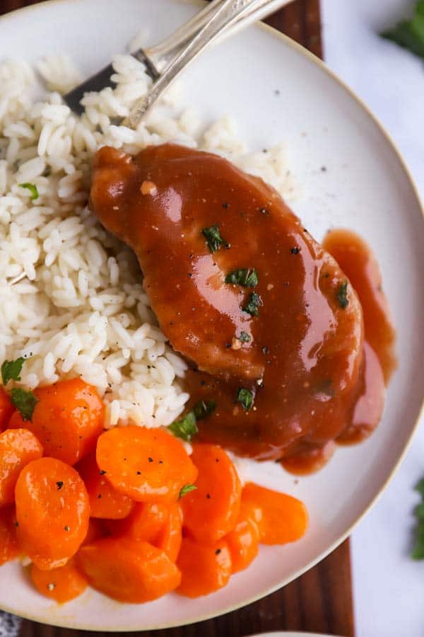 close up of a plate with rice, carrots and glazed pork chops