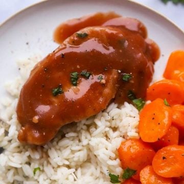 close up of a plate with rice, carrots and glazed pork chops
