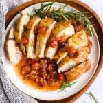 sliced turkey breast and cranberry sauce on a plate set on a wooden platter