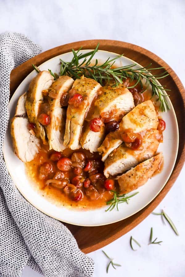 sliced turkey breast and cranberry sauce on a plate set on a wooden platter