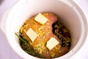 crockpot with cranberries, rosemary and raw turkey breast