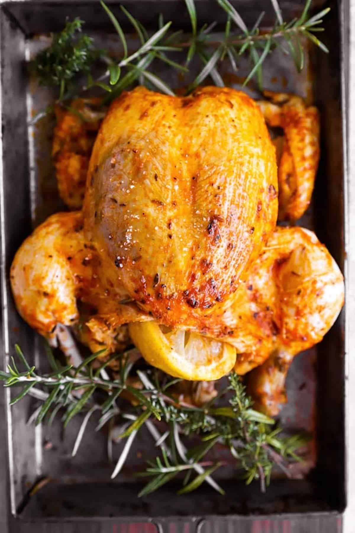 Whole slow cooker chicken on a sheet pan with fresh rosemary