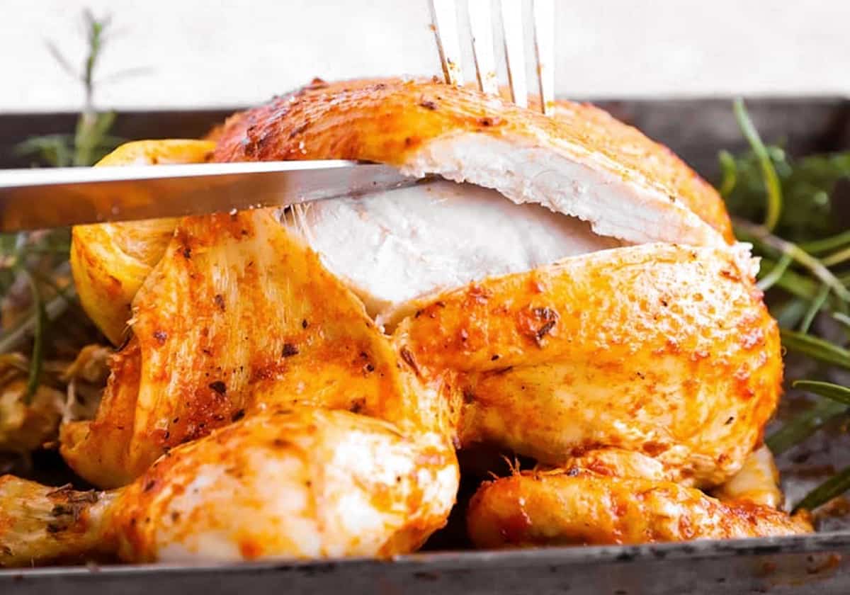 fork and knife slicing a rotisserie chicken