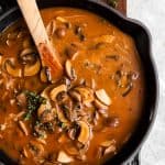 cast iron skillet with mushroom gravy on a wooden board