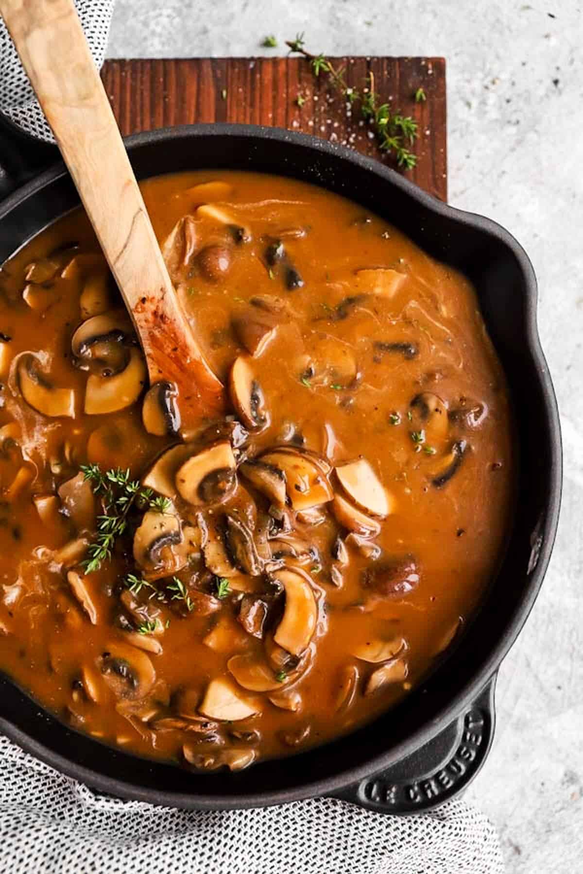 cast iron skillet with mushroom gravy on a wooden board