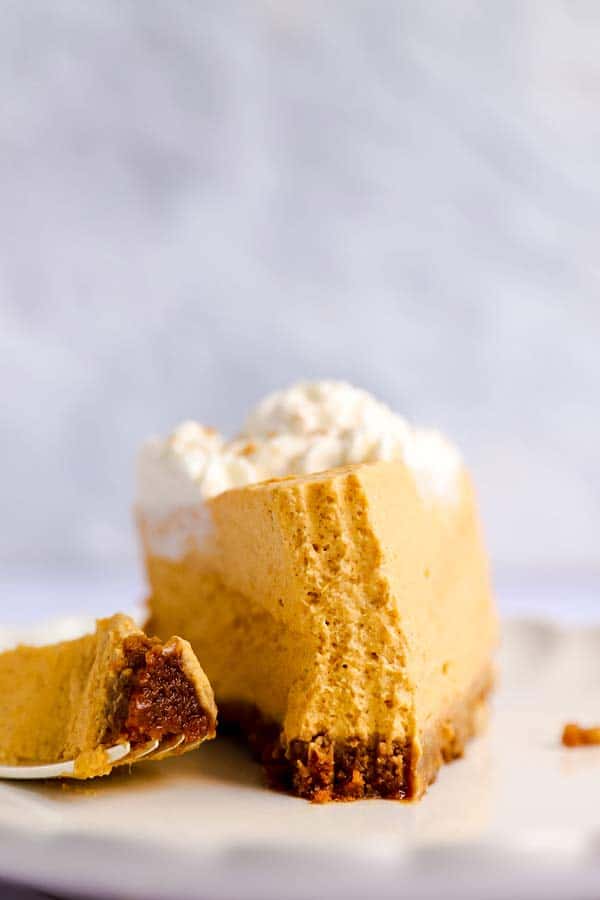 frontal view of a slice of no bake pumpkin cheesecake with a bite taken out