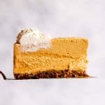 slice of no bake pumpkin cheesecake in front of a light colored wall