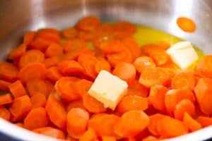 cooked carrots in a pan with butter and ingredients for orange glaze