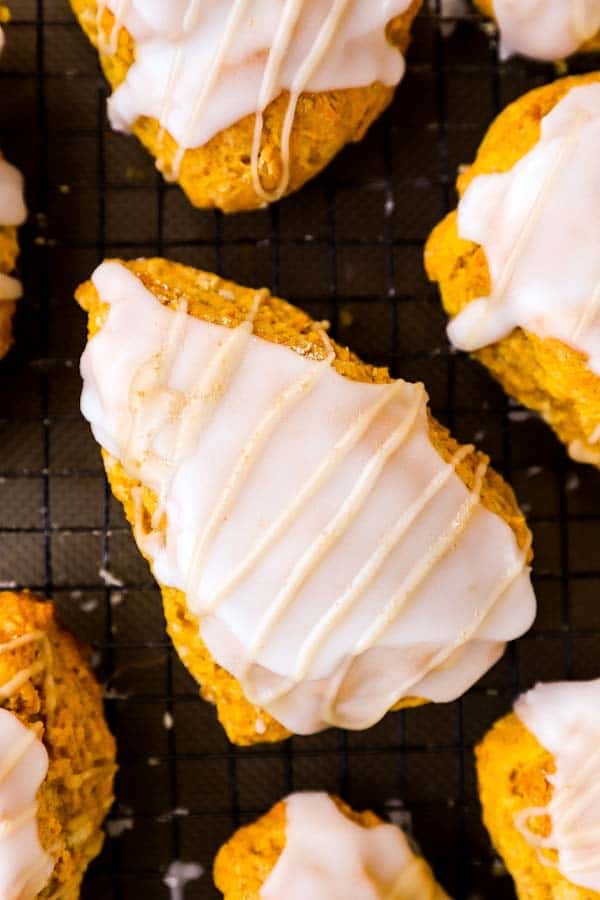 close up photo of a glazed pumpkin scone on a cooling rack