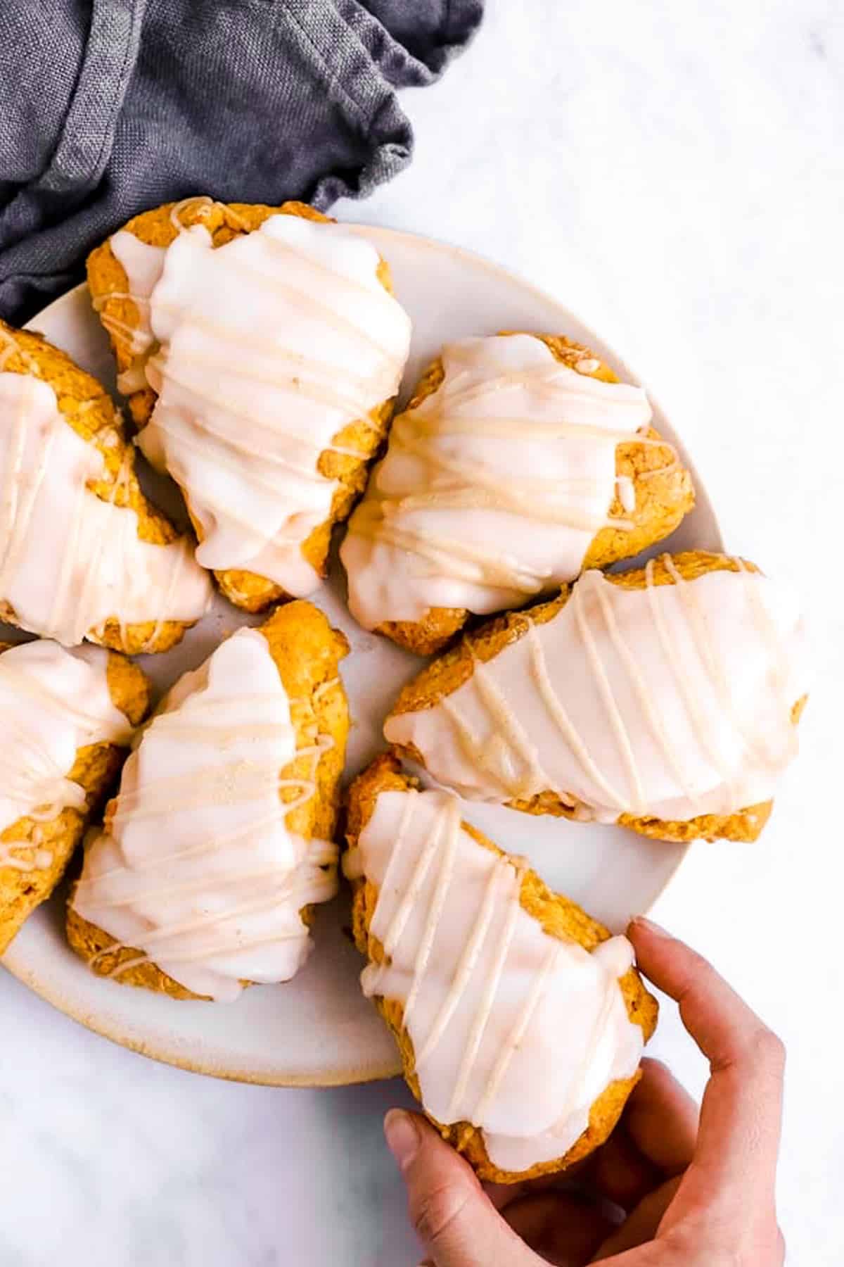 female hand taking pumpkin scone from plate