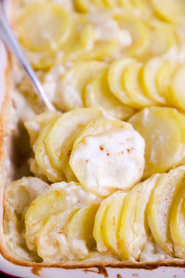 scooping scalloped potatoes out of a dish with a spoon