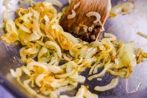 sautéed onions in a skillet with a wooden spoon