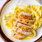 sliced chicken breast on a plate of pasta