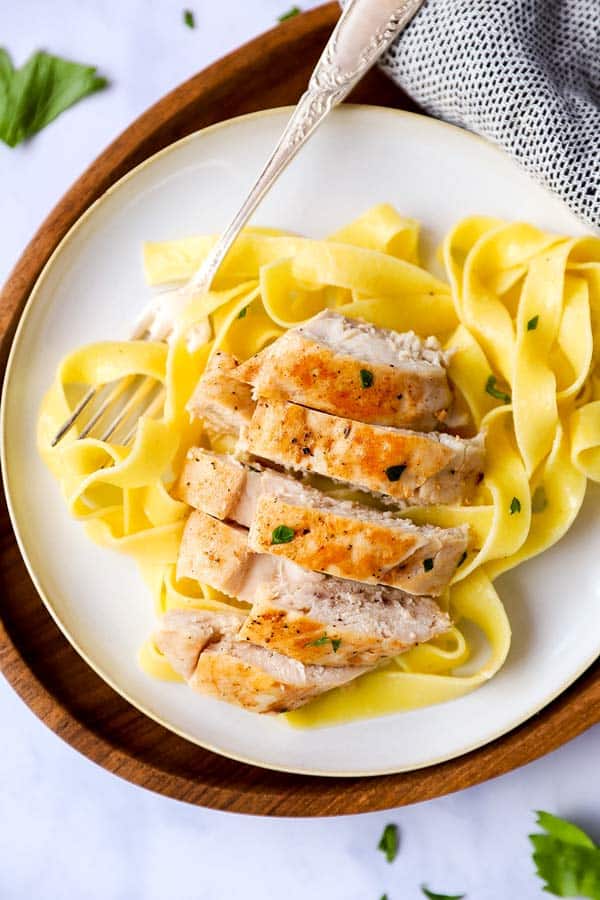 sliced chicken breast on a plate of pasta