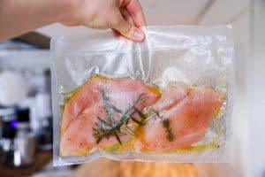 holding a sous vide bag with uncooked chicken