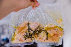 holding a sous vide bag with cooked chicken