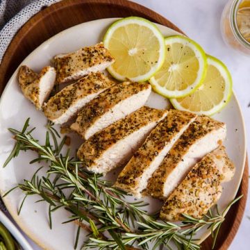 sliced turkey breast on a platter with lemon slices and fresh rosemary