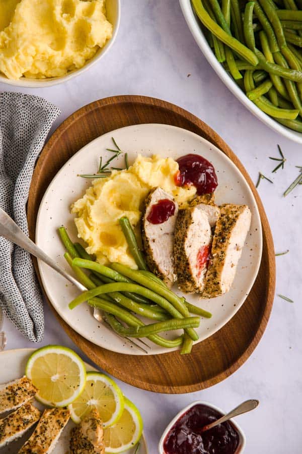 sliced turkey breast on a plate with mashed potatoes and green beans