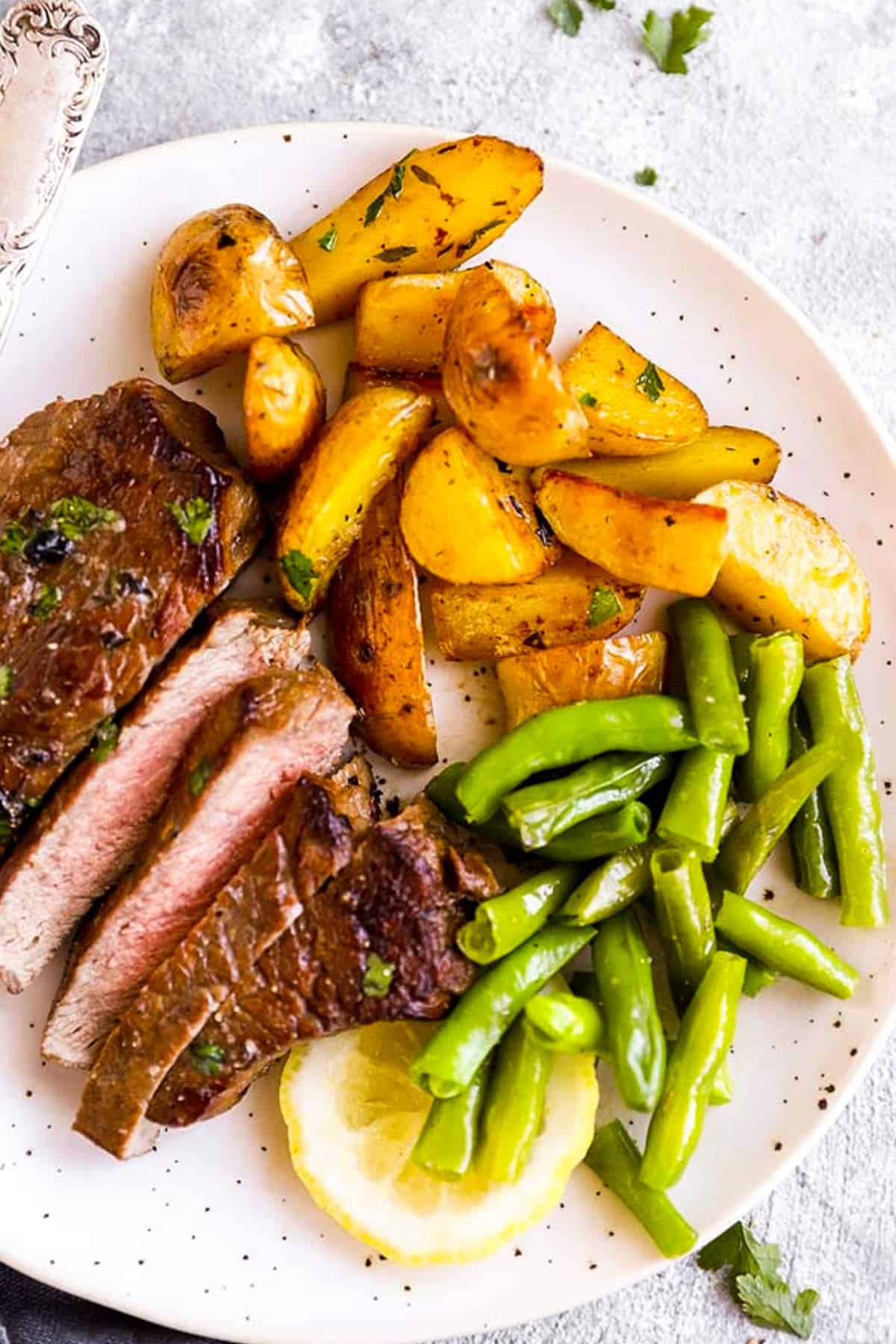 plate with sliced steak, potatoes and green beans