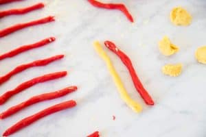 ropes of colored sugar cookie dough on a white marble surface