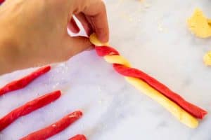 twisting a red and a white rope of cookie dough together