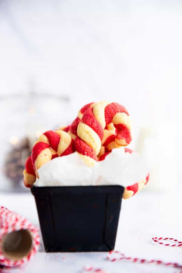 black loaf pan lined with parchment paper and filled with candy cane cookies