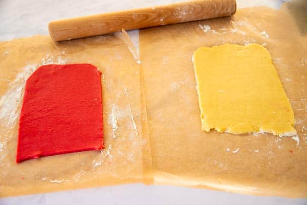 red and plain sugar cookie dough rolled out on wax paper