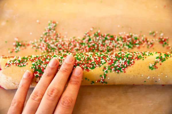 rolling log of sugar cookie dough in sprinkles