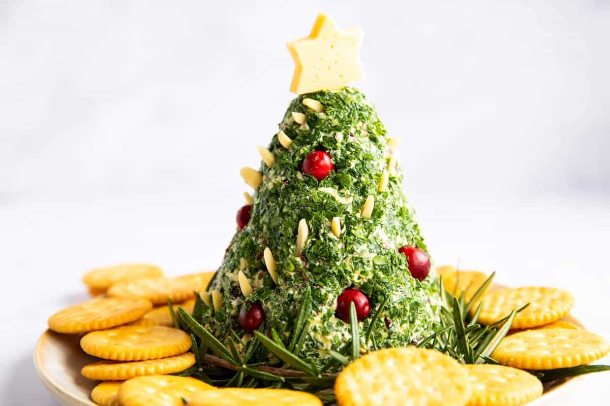 Christmas tree shaped cheeseball on a platter with crackers