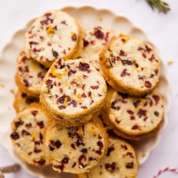 plate filled with cranberry orange shortbread cookies on a marble surface