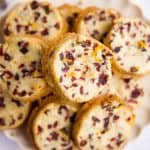 close up of a plate filled with cranberry orange shortbread cookies on a marble surface