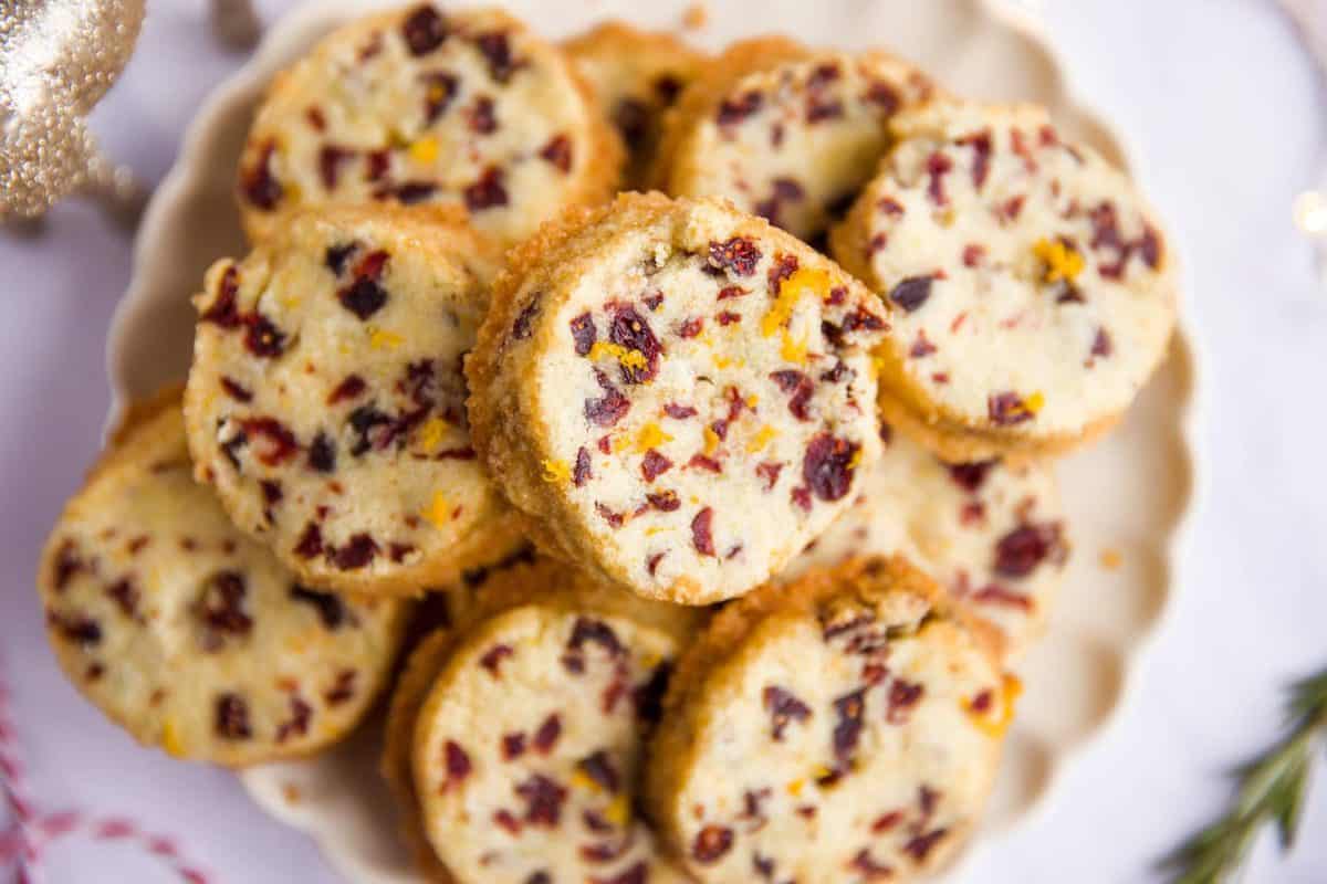 close up of a plate filled with cranberry orange shortbread cookies on a marble surface
