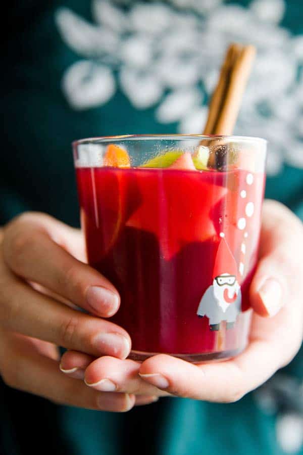 woman in green sweater holding a glass of Christmas punch