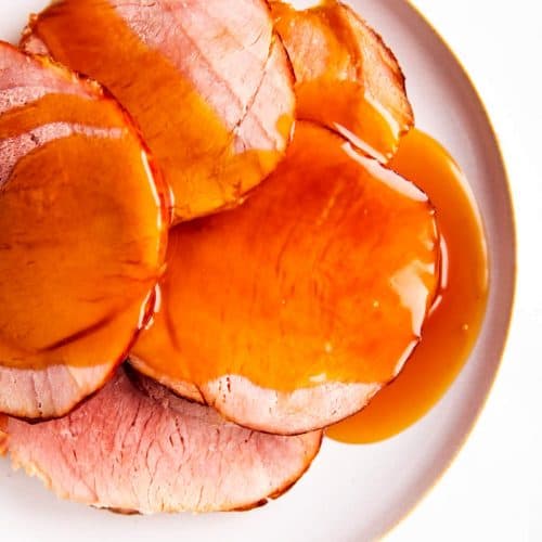 white plate with slices of ham covered in honey glaze
