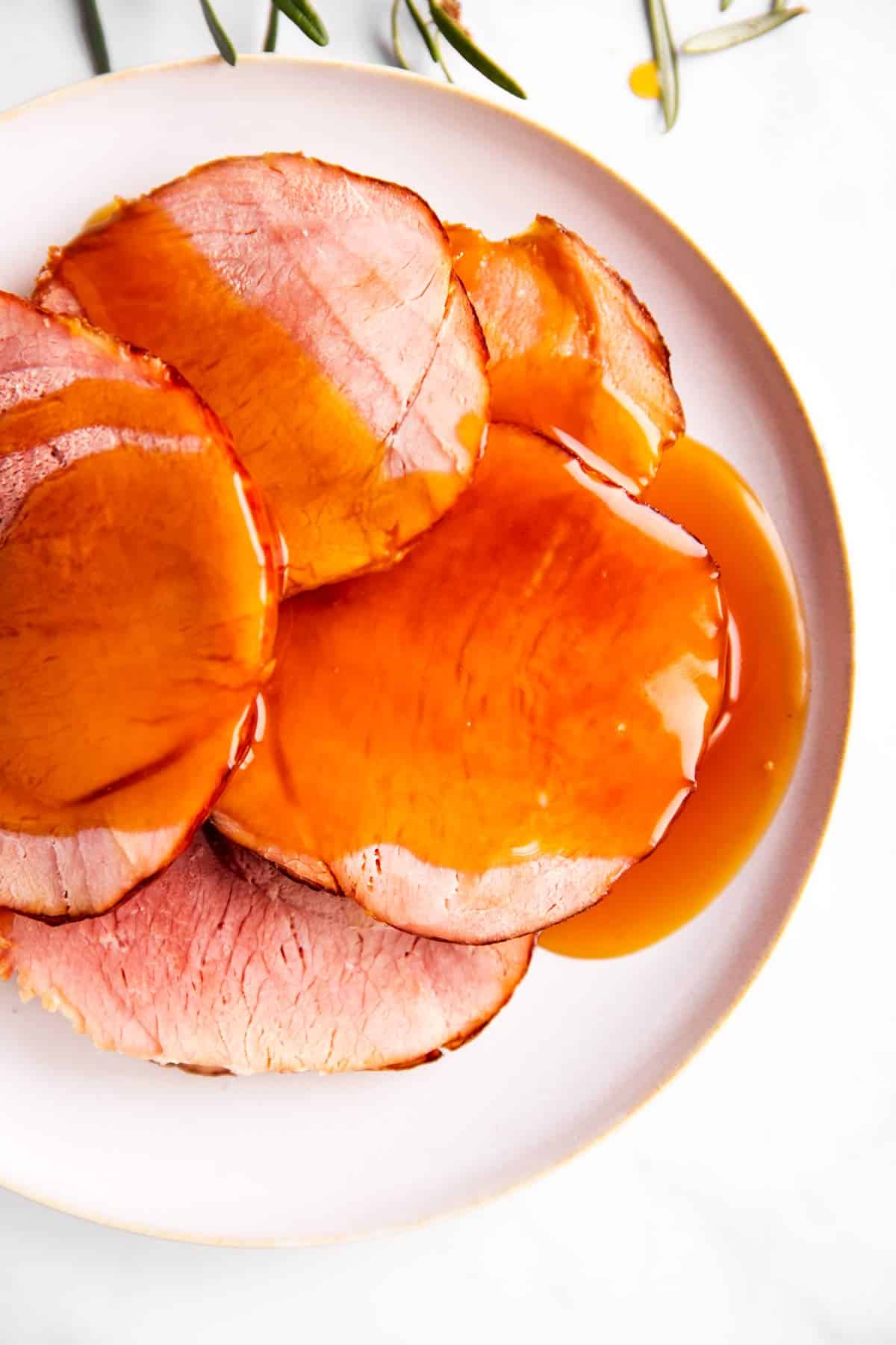 white plate with slices of ham covered in honey glaze